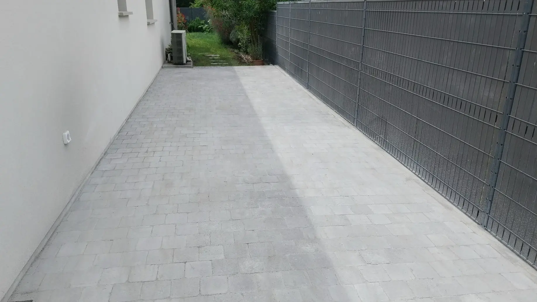 Photo de l'allée de jardin en pavés carrossables après sa réalisation par nos paysagistes. On voit les pavés arpès la réalisation des joints et du ponçage. 