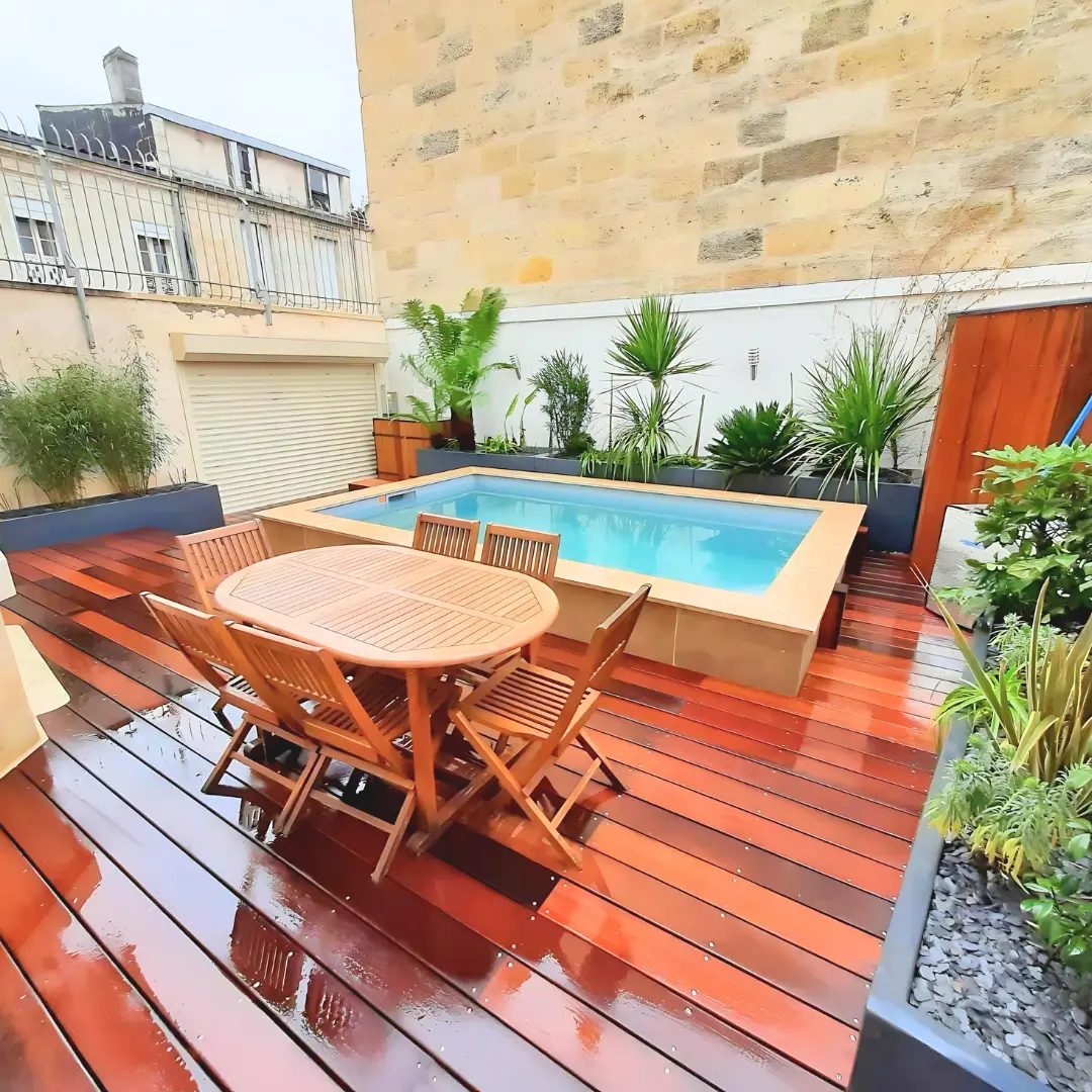 Photo d'un aménagement de terrasse à Bordeaux avec la pose de terrasse en bois exotique et la réalisation de massifs exotiques dans des jardinières 