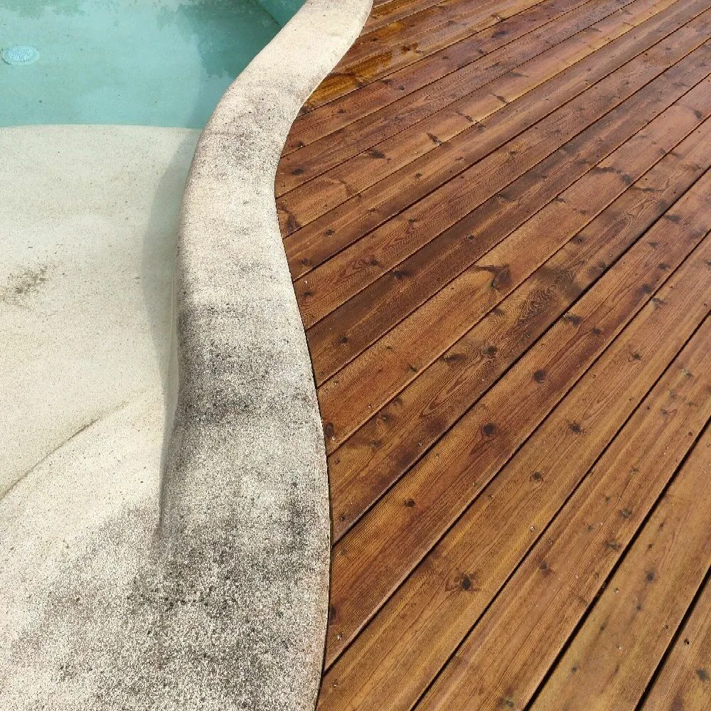 Pose de la terrasse bois avec des découpes parfaites pour s'adapter aux courbures de la piscine. 